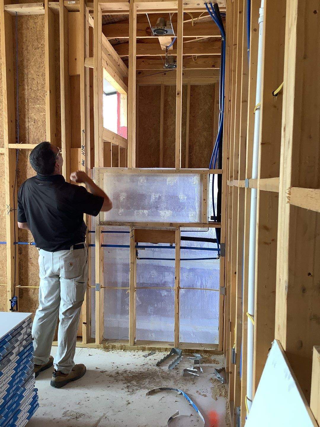 Field observer documenting a framed interior before drywall