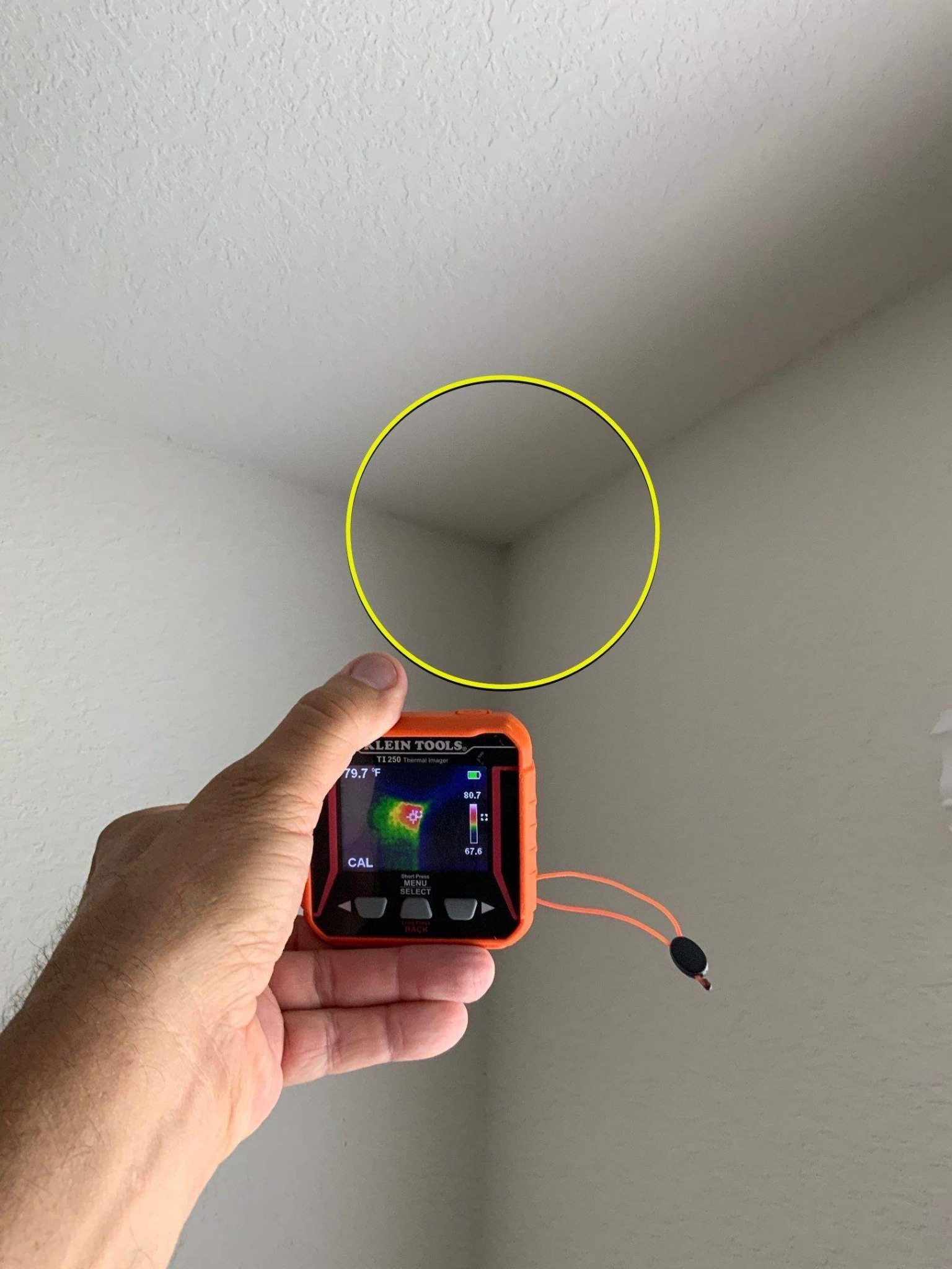 Handheld thermal camera aimed at an interior corner